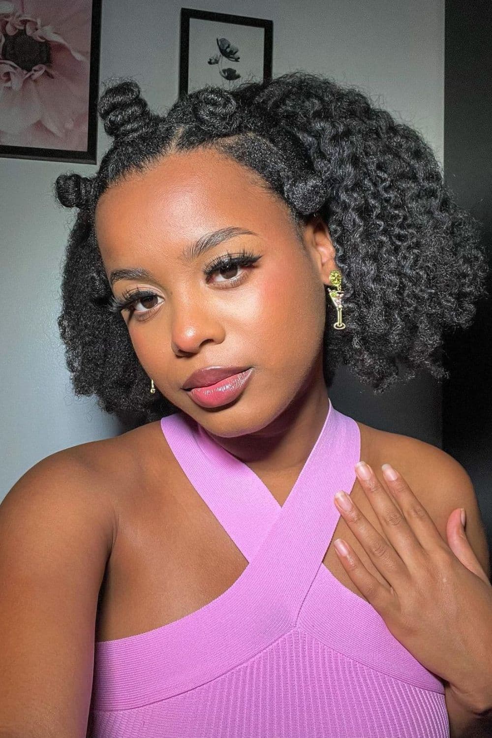 A black woman in a pink halter top with a Bantu knot crown.