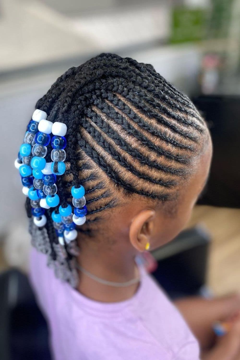 Side view of a girl with a beaded two-strand twist mohawk updo.