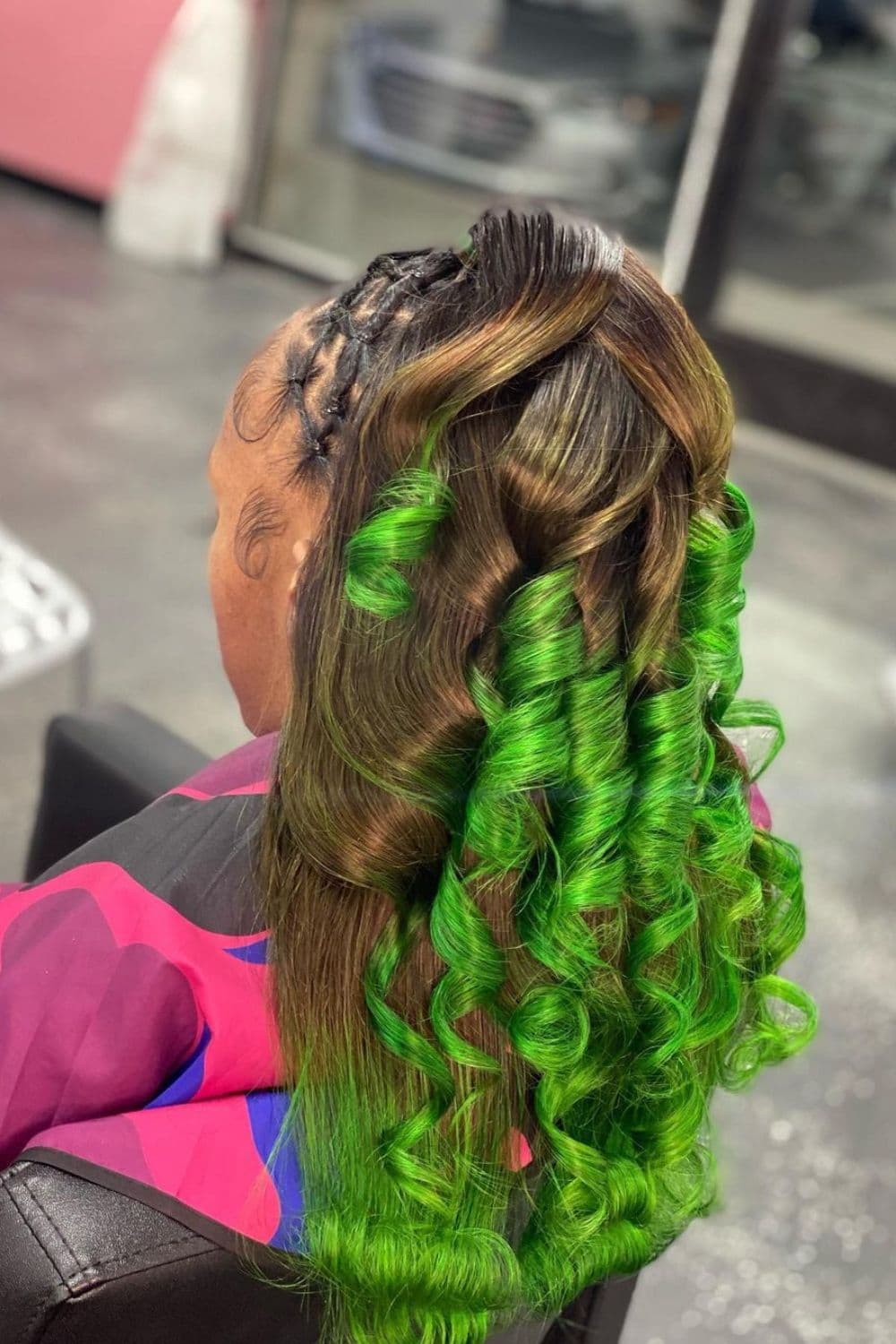 Back view of a woman with a crisscross half up half down hairstyle with green curls.