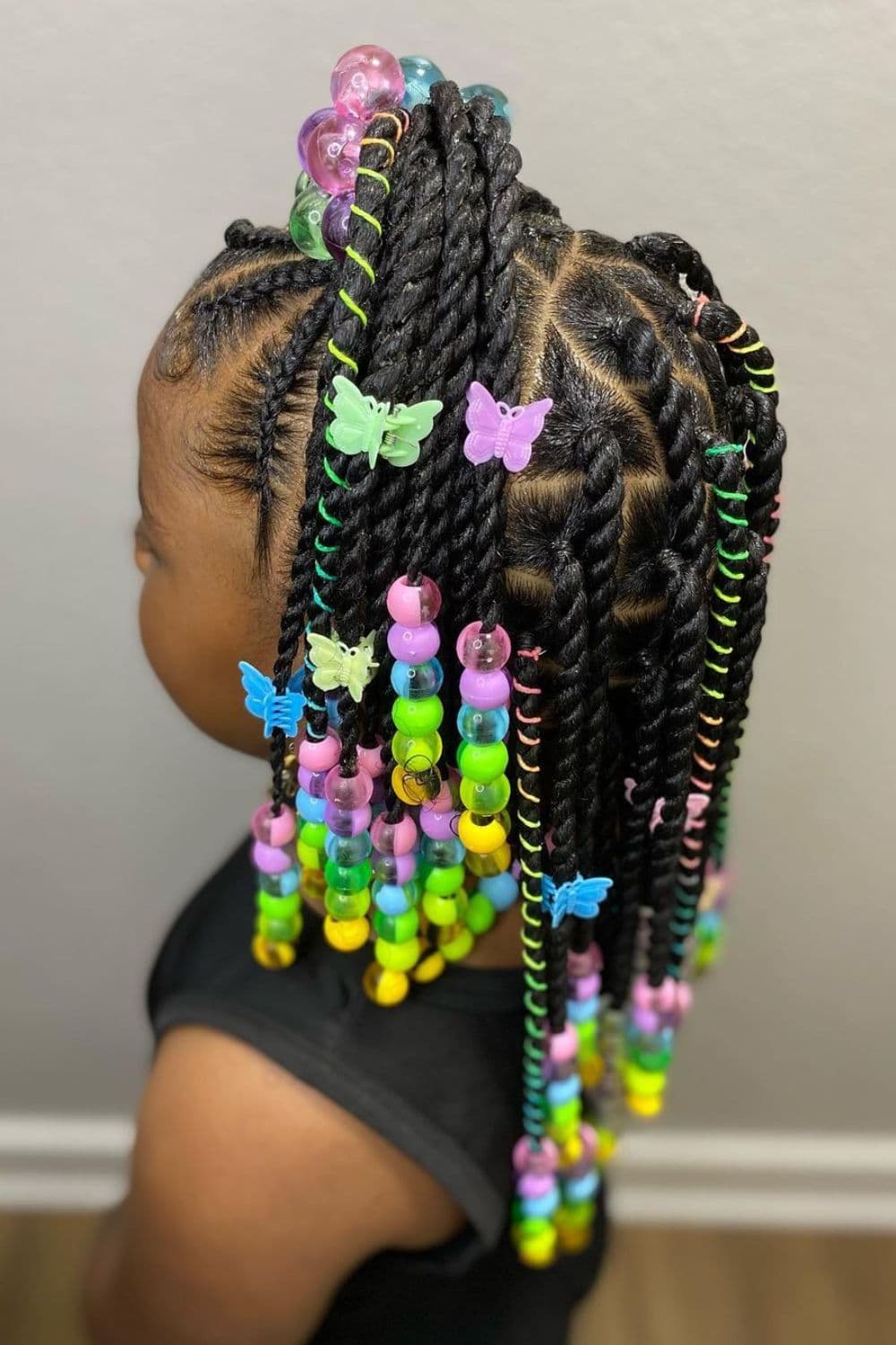 Side view of a little girl with double-sided braids with colorful beads.
