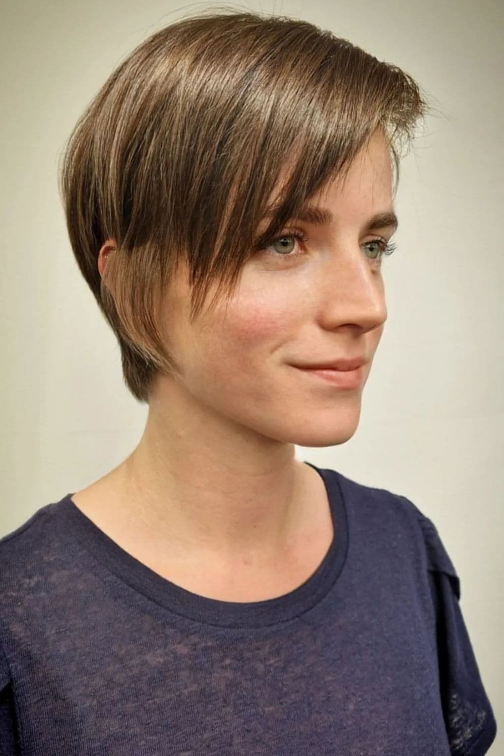 A woman in a black t-shirt with a graduated pixie cut.