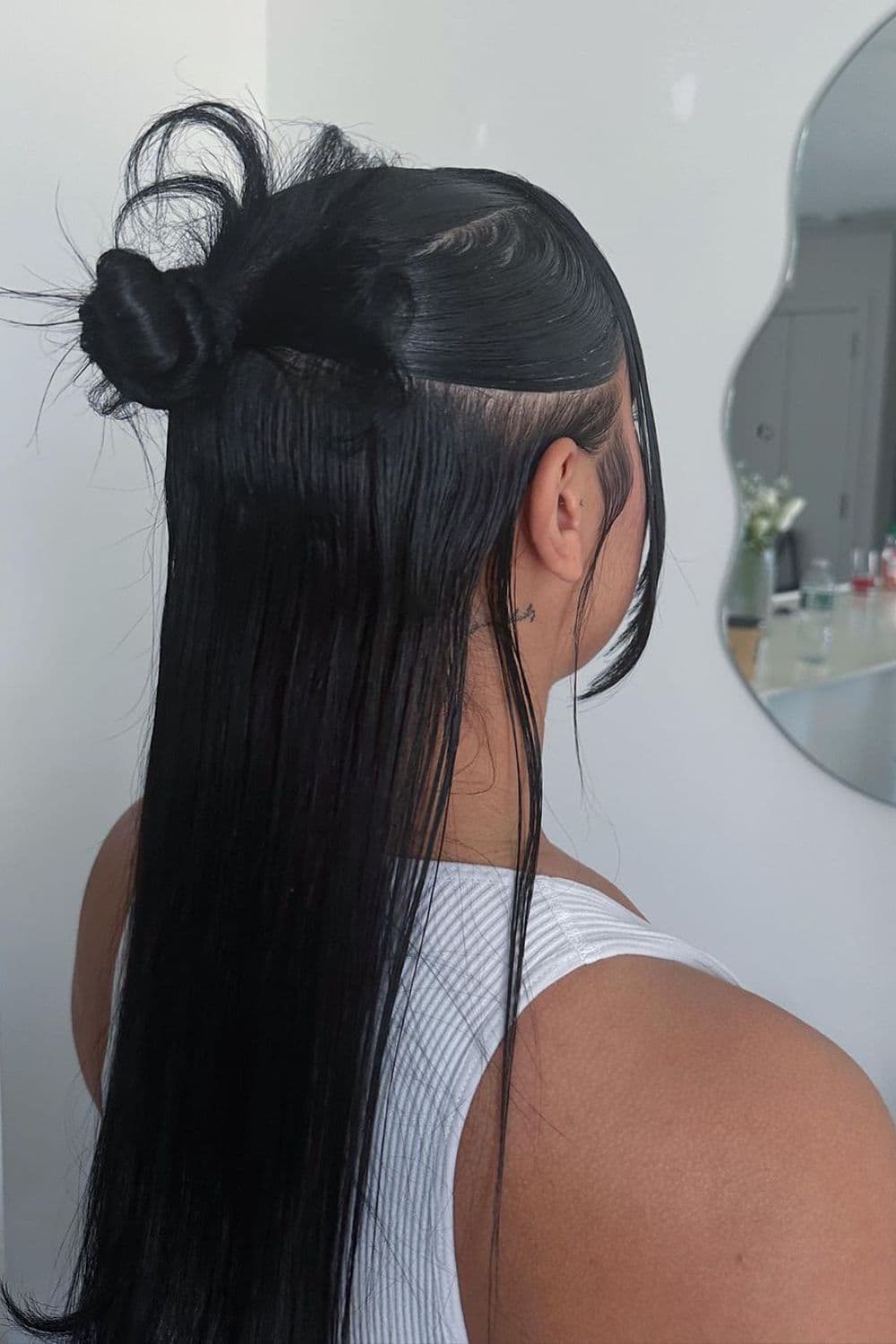 A woman with black hair with a half up half down bun.