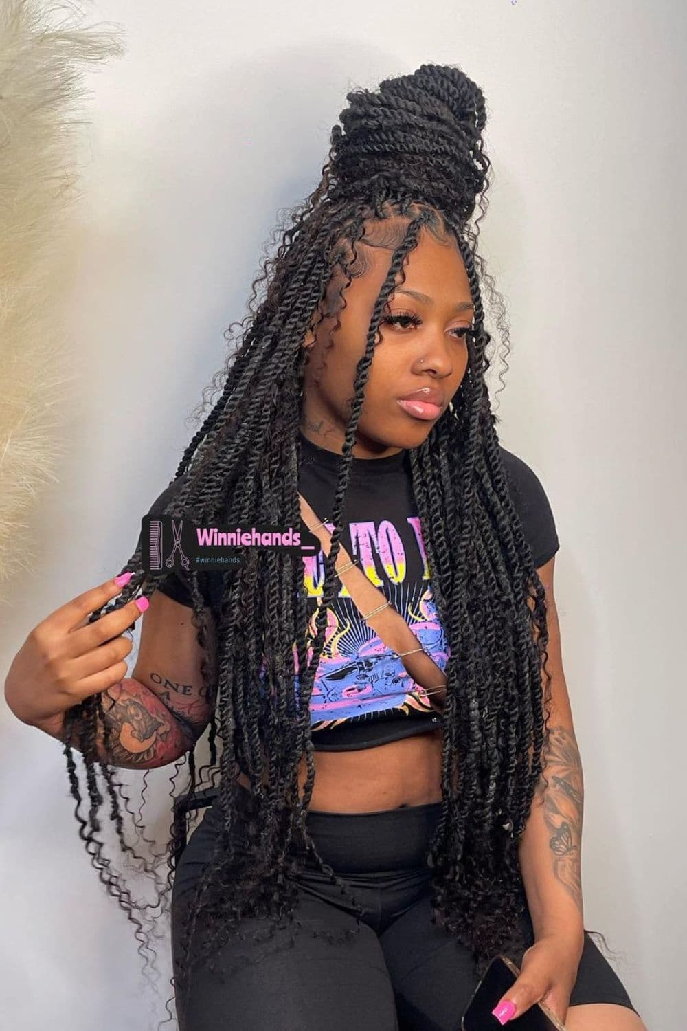 A woman in a black crop top and yoga shorts with half up half down with Faux Locs hairstyle.