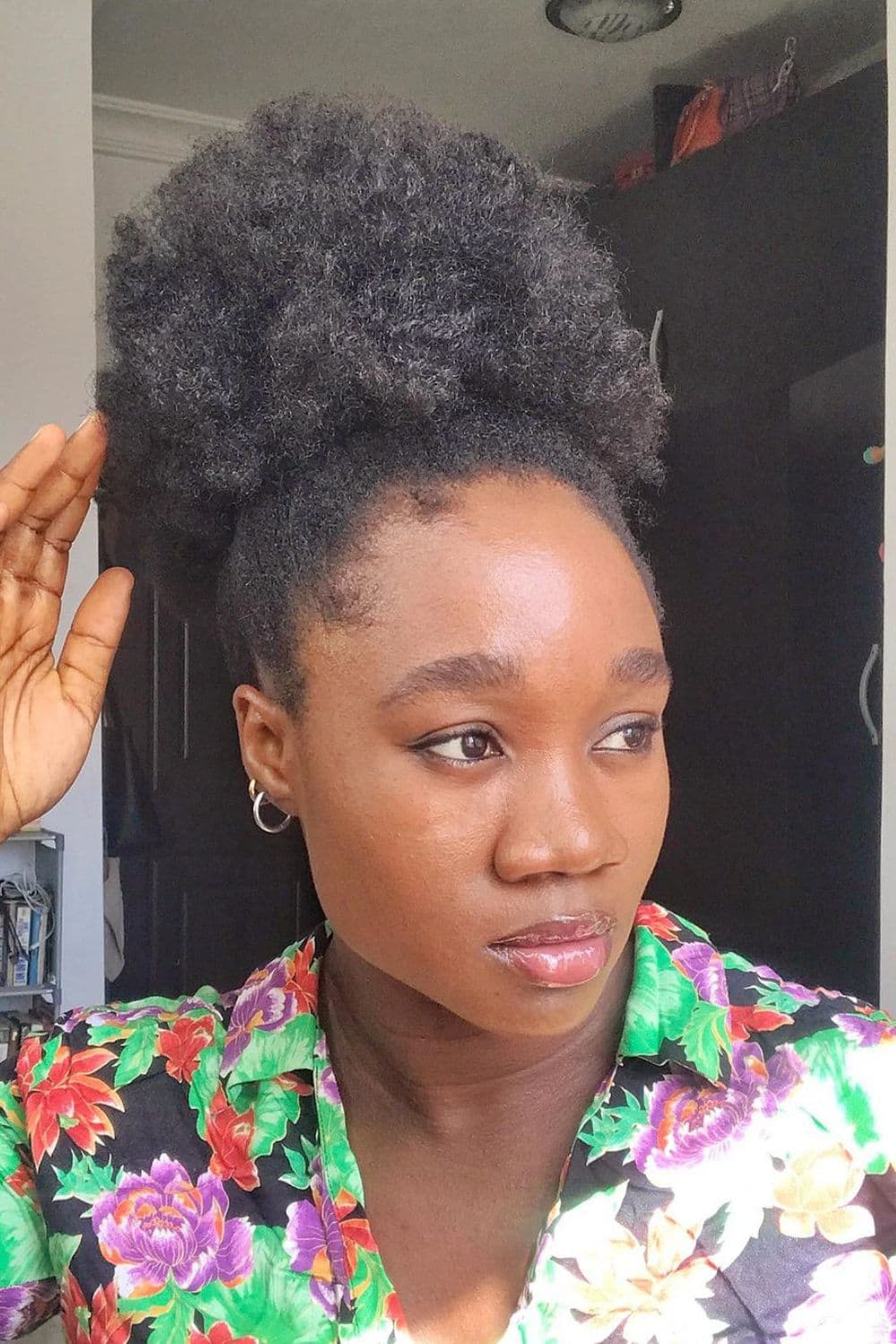 Woman with a floral polo shirt in a high puff hairstyle.