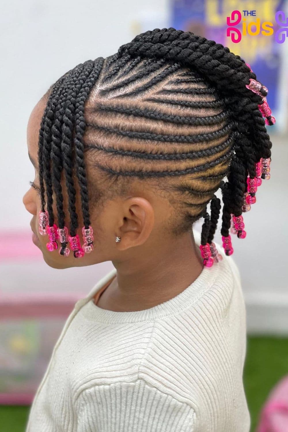 Side view of a girl with a mohawk cornrows with pink beads.