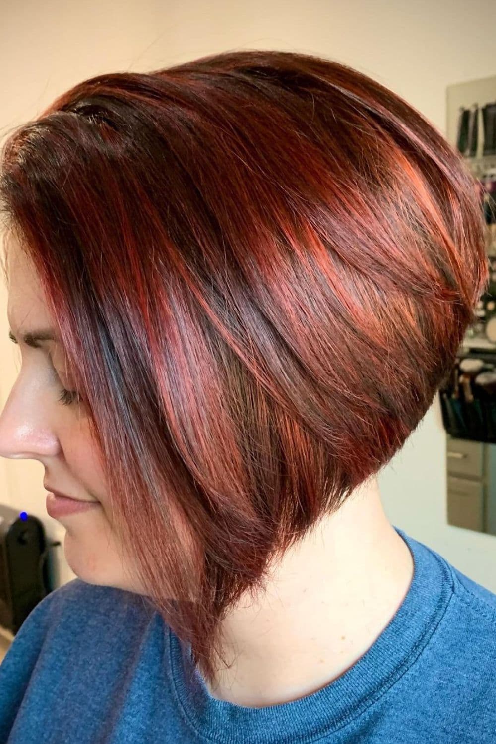 A woman with a stacked bob cut and red highlights.