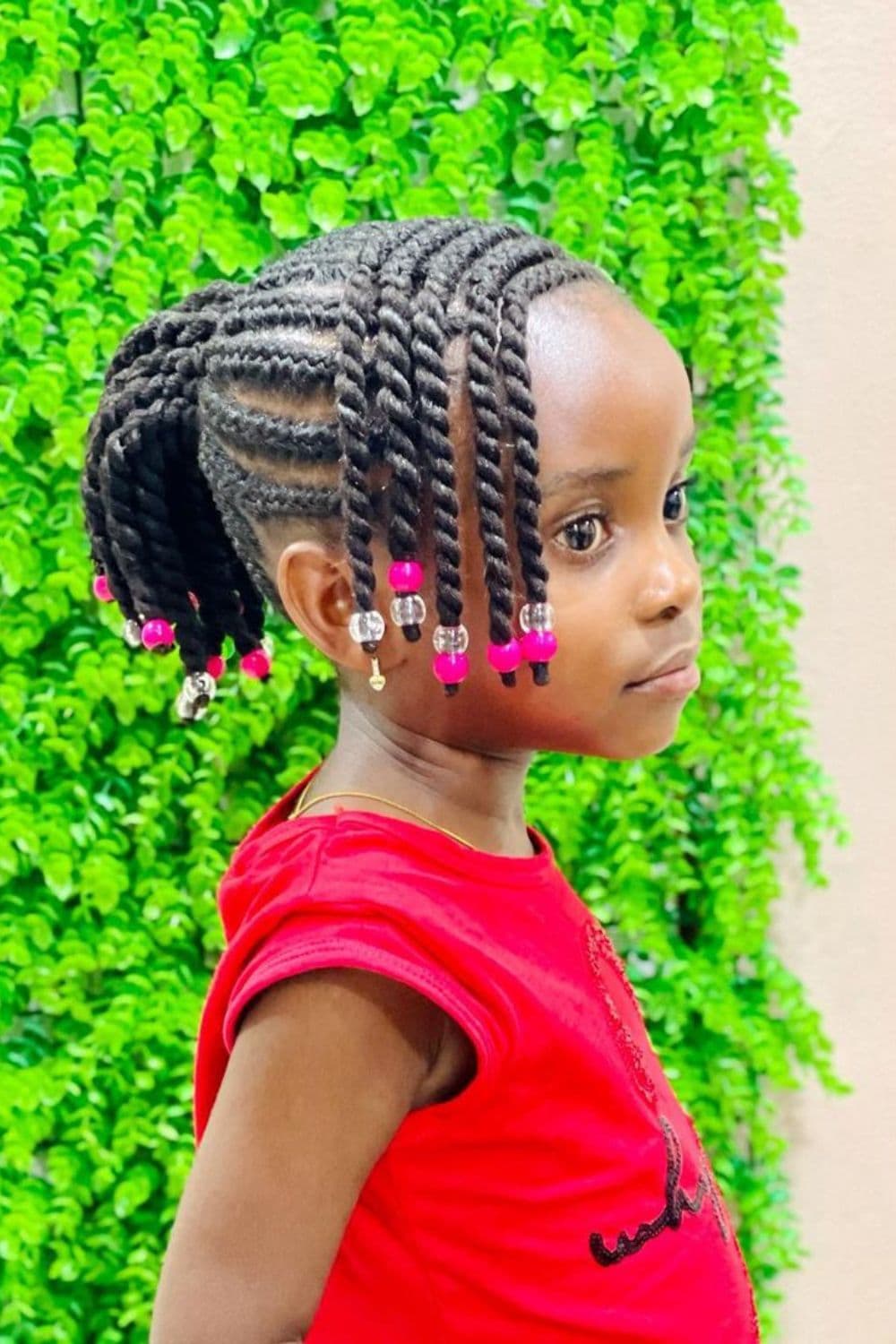 Side view of a girl with threaded cornrows with pink and clear beads.
