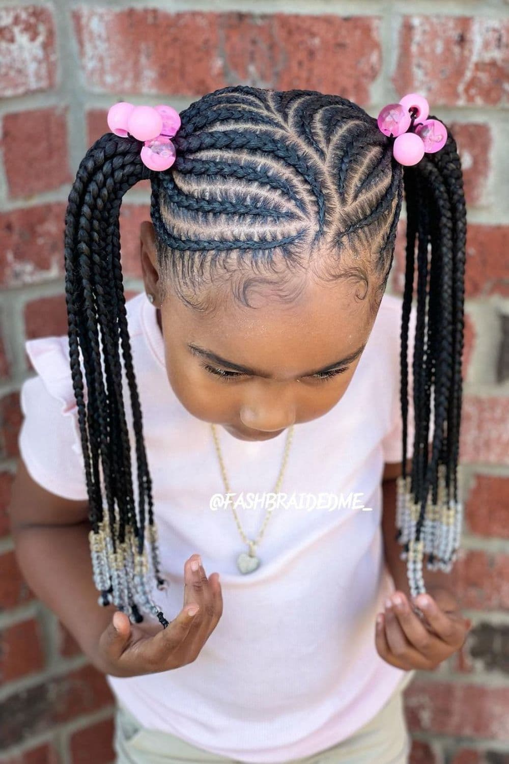A little girl with two-sided braids with pink and clear beads.