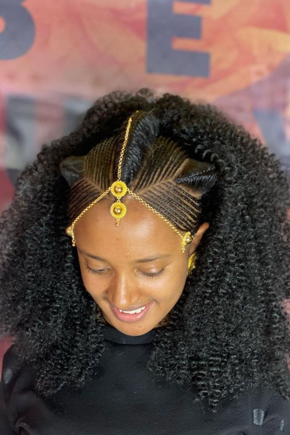 A woman with Albaso braids with gold hair accessory.