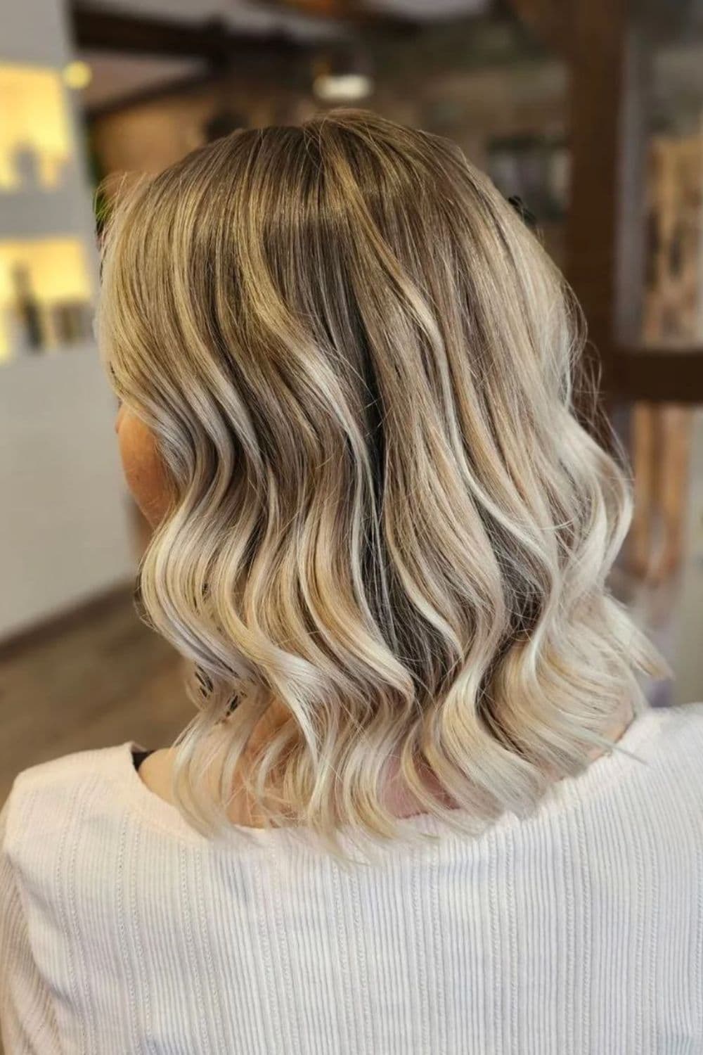 A woman with a wavy blonde and black balayage bob hair.