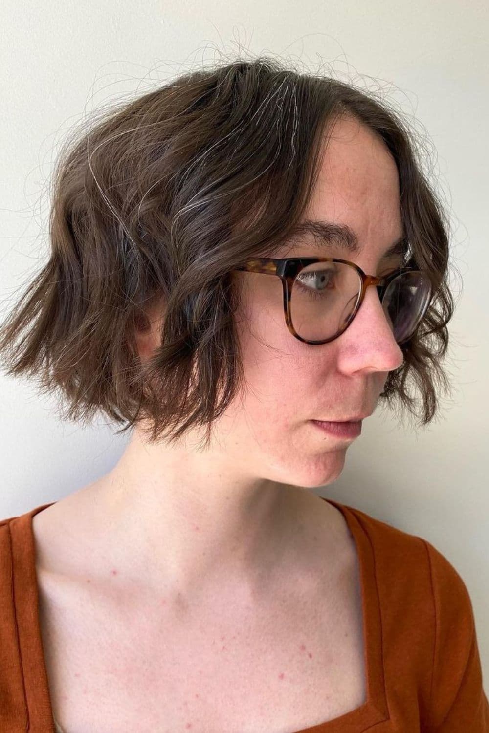 Side view of a woman with beach wave bob and eyeglasses.