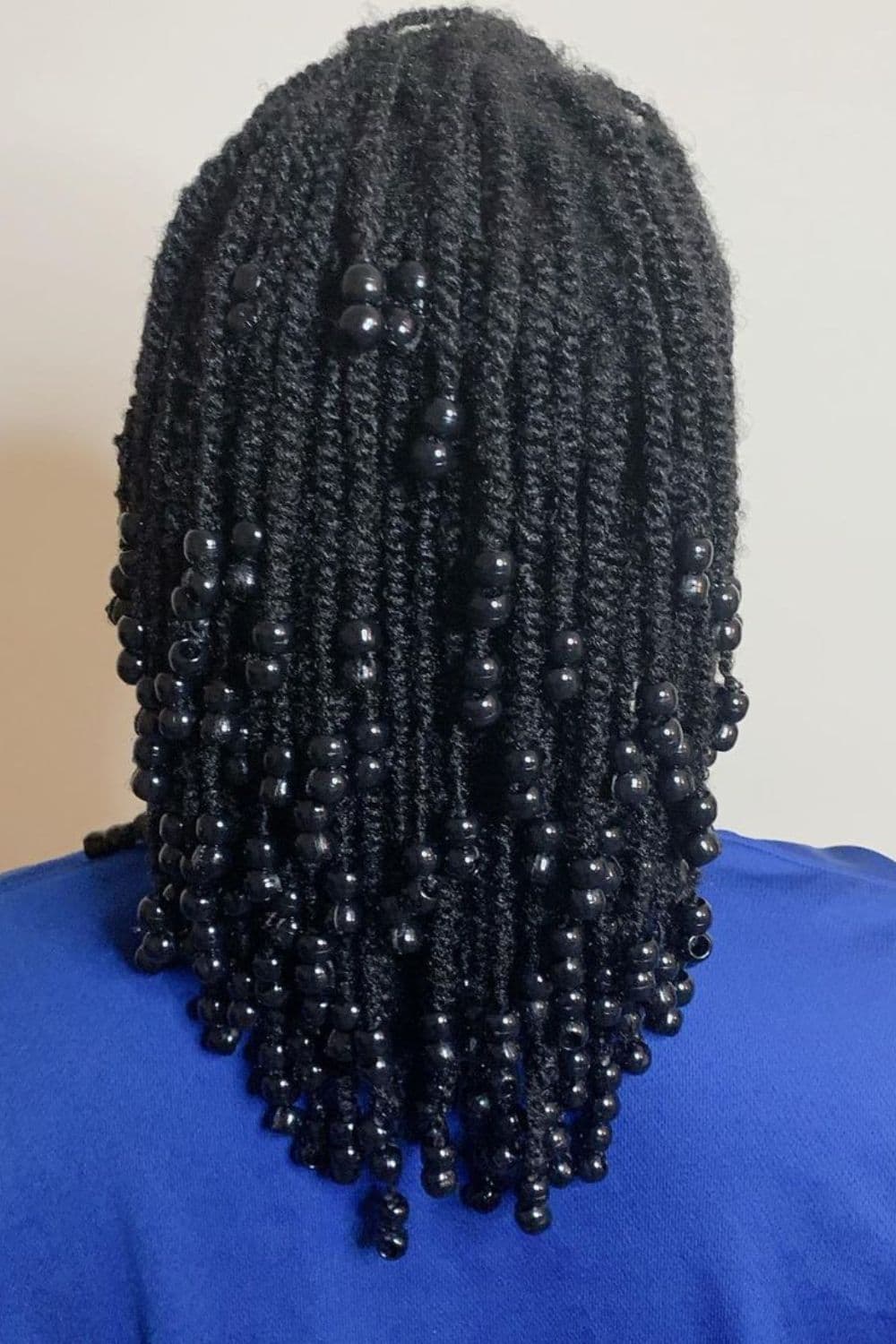 A person with two-strand twists with black beads on ends.