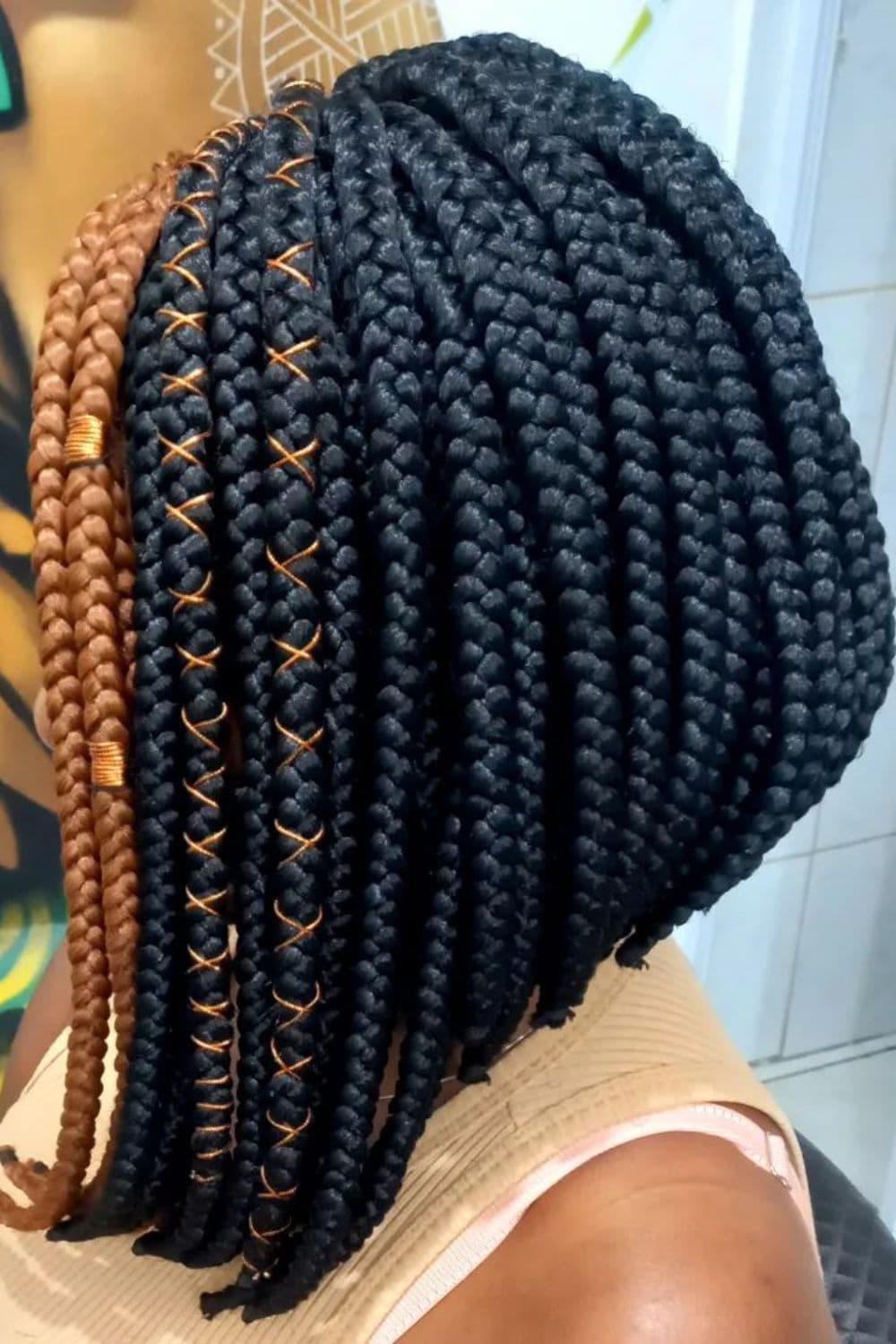 Side view of a woman with black and brown box braids and brown thread.