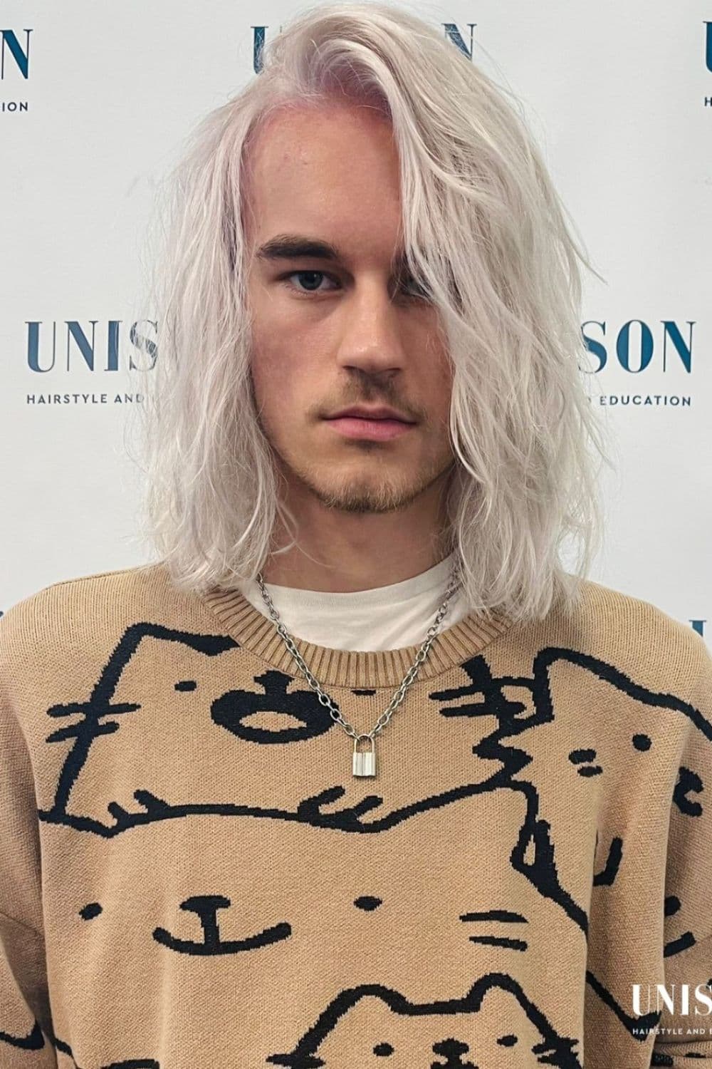 A man wearing a cat print brown sweater with bleached blonde wolf cut.