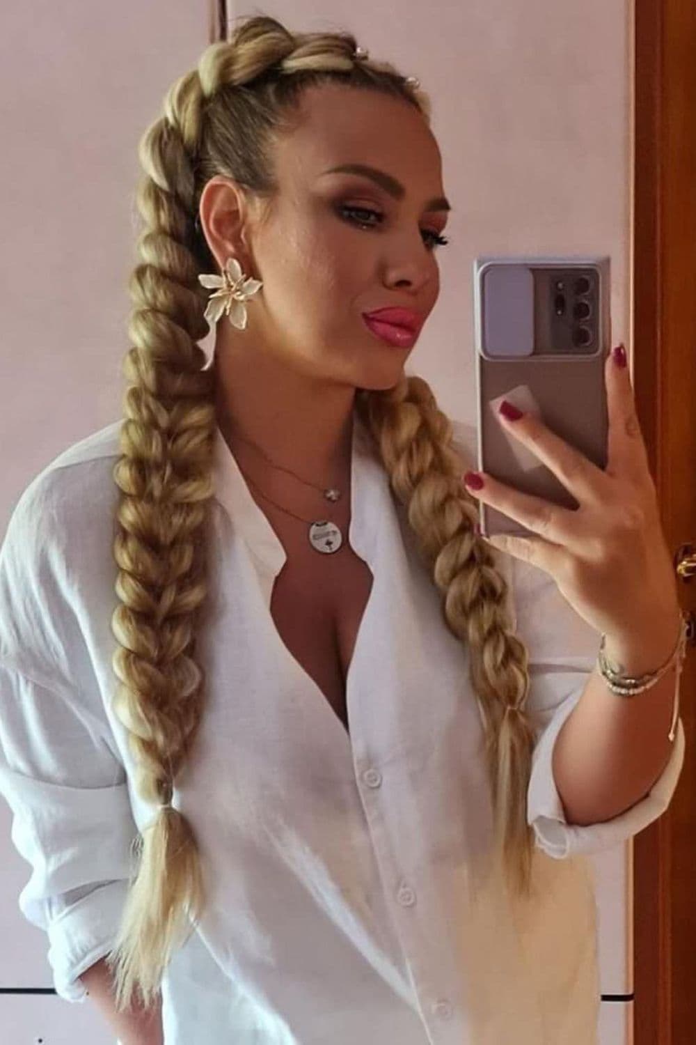 A woman with a blonde butterfly braid taking a selfie with her phone.