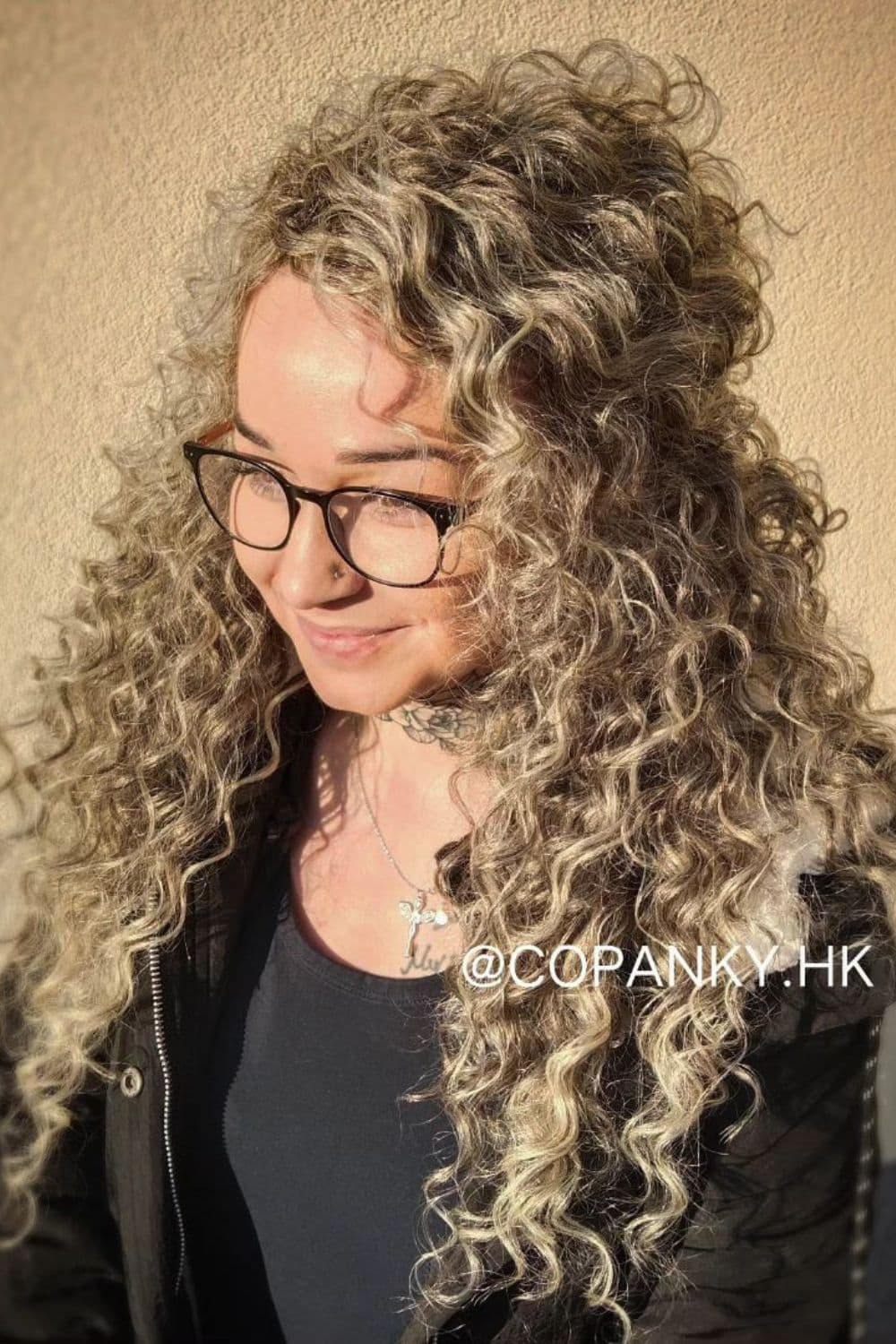 A woman with blonde crochet curls and eyeglasses.
