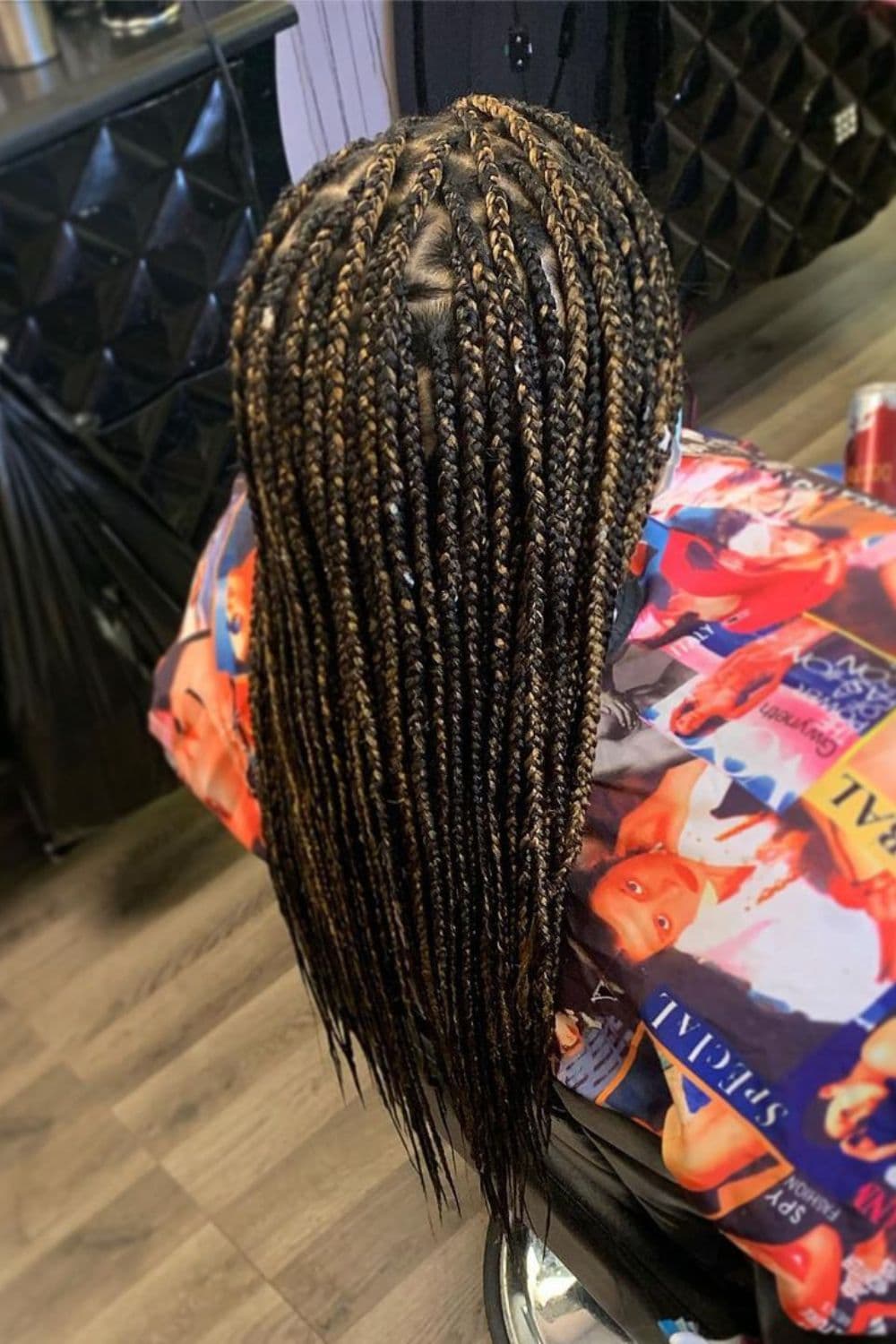 A woman sitting in a hair salon with blonde highlighted knotless braids.