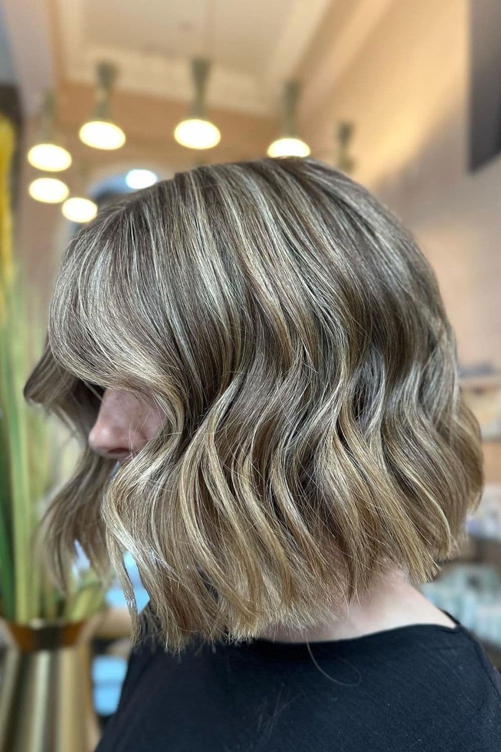 Side view of a woman with wavy bob with babylights.