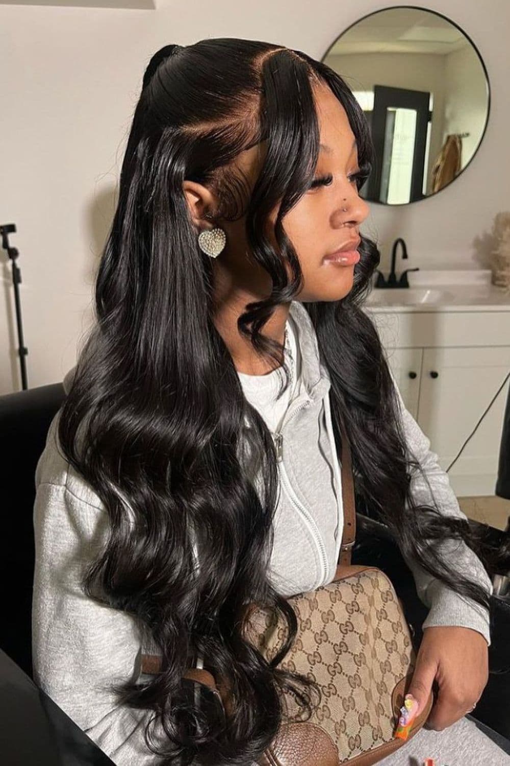 Side view of a woman with a black body wave half up half down hairstyle.