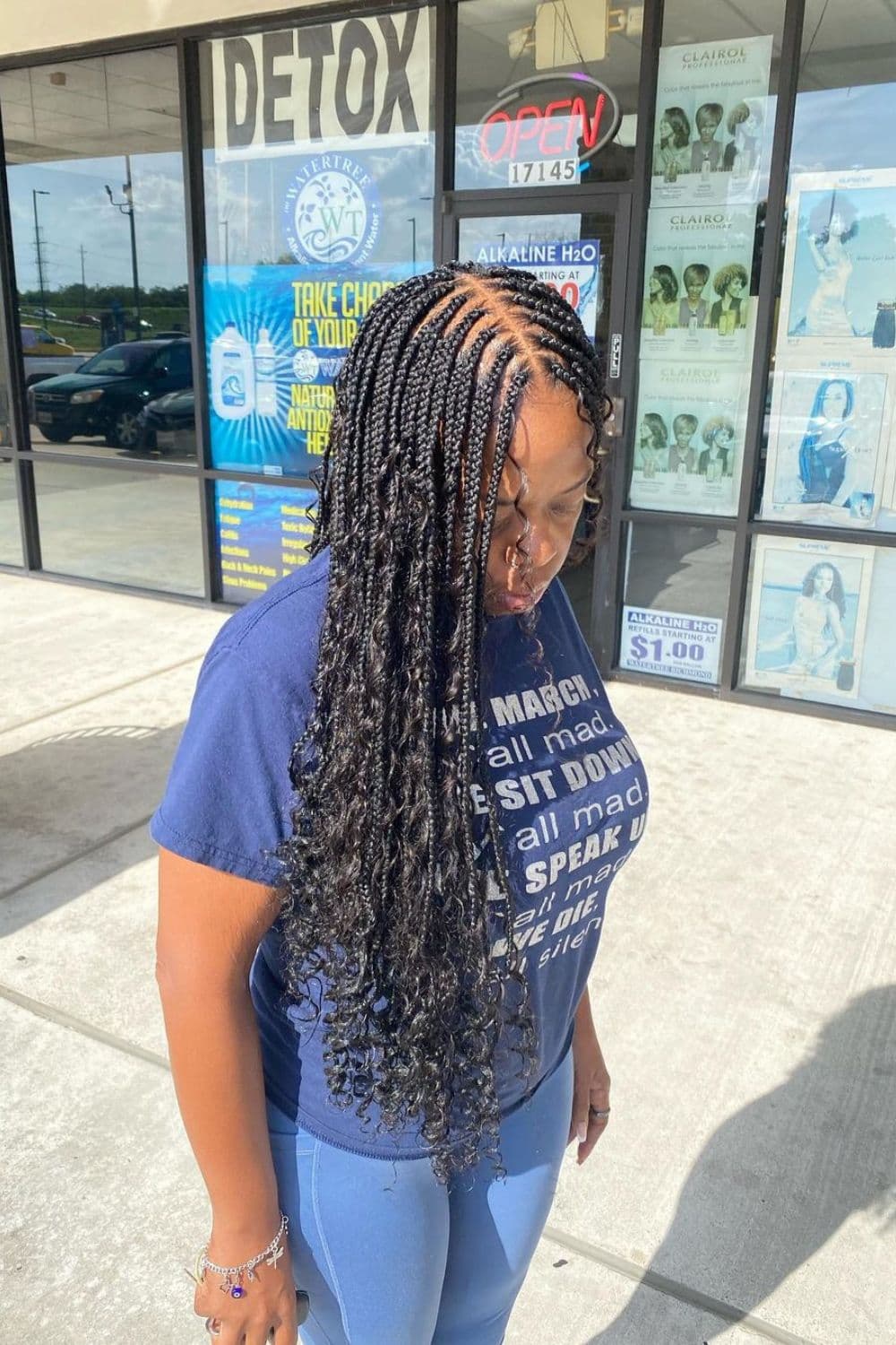 Side view of a woman with black Boho box braids with curly ends.