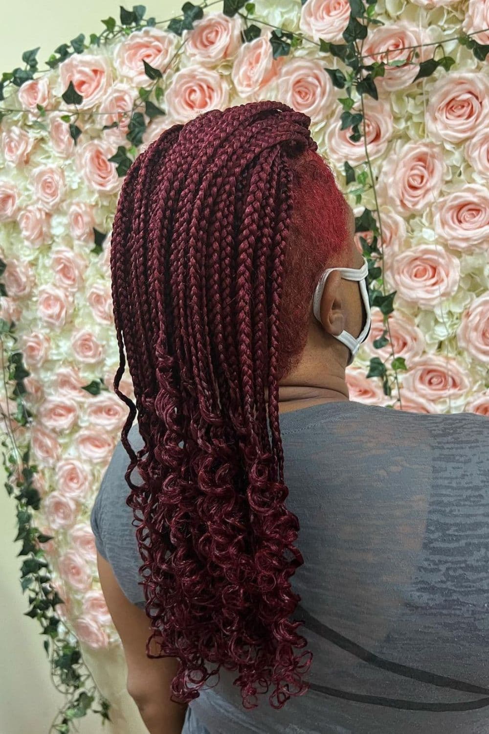A woman with red hair with box braids mohawk and curly ends.
