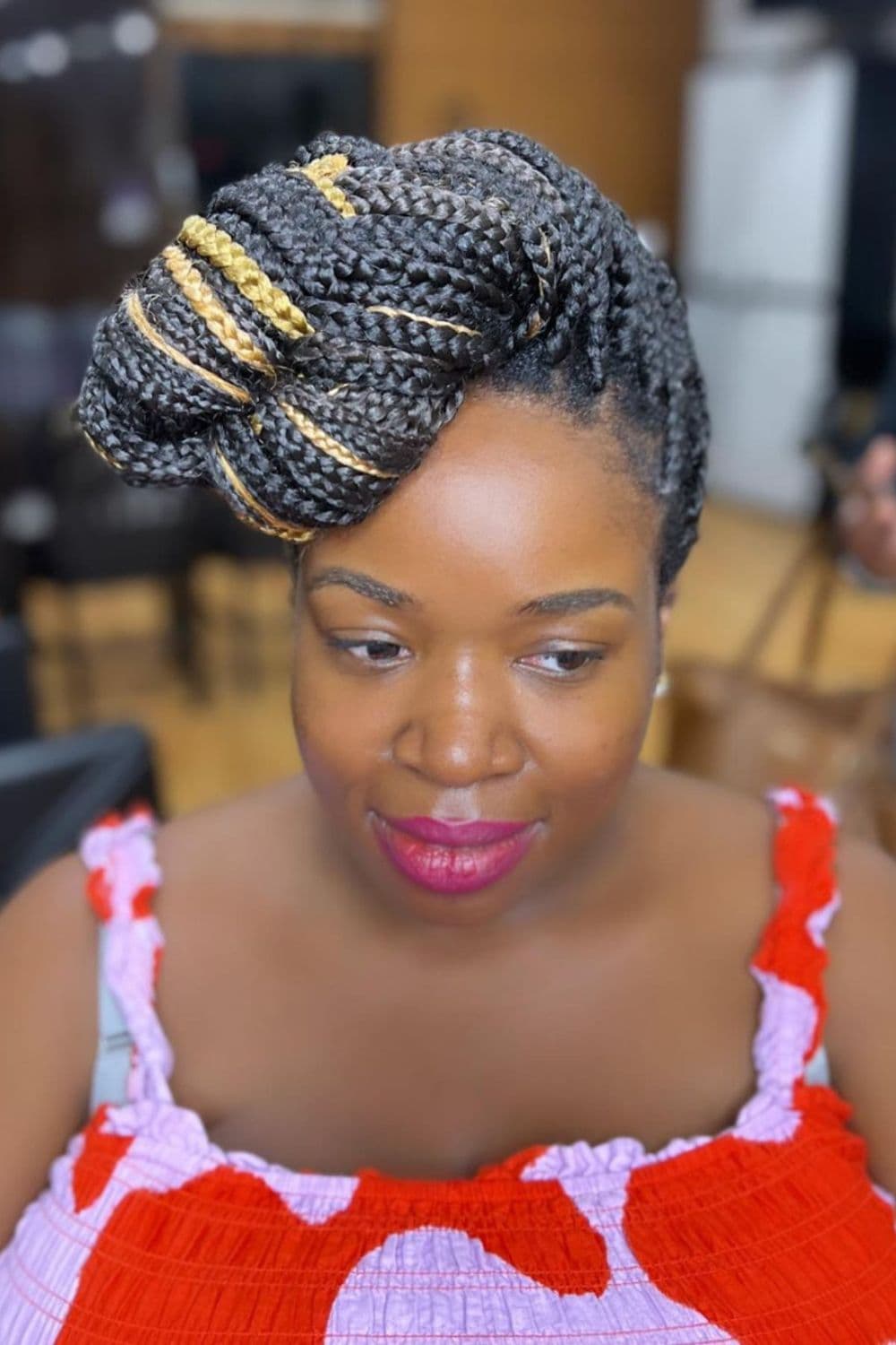 A woman with black and gold box braids updo.