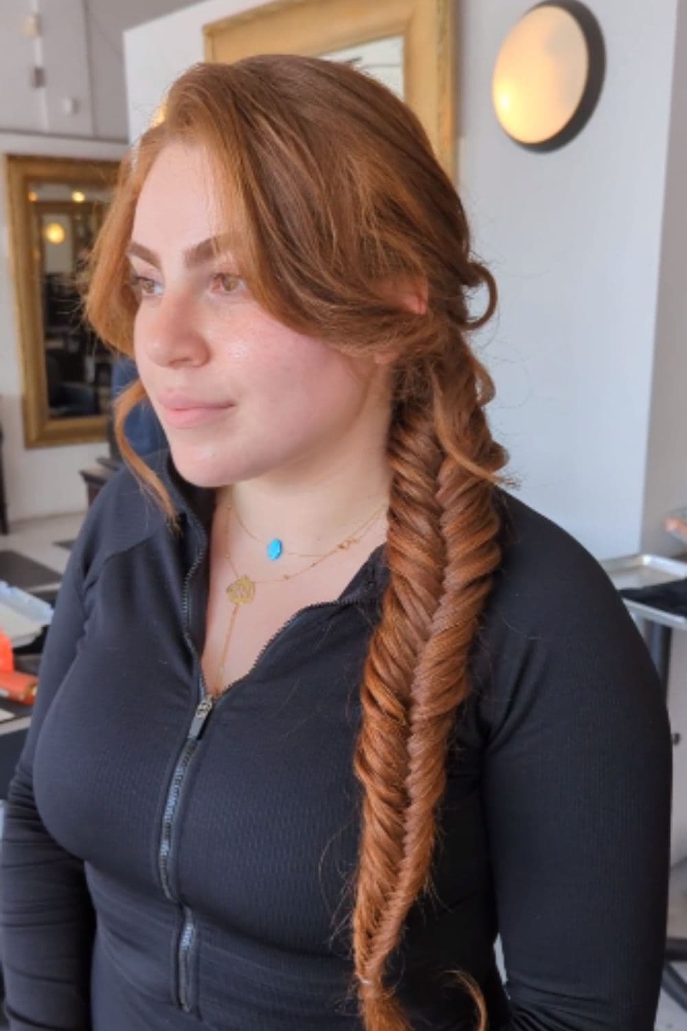 Side view of a woman with brown fishtail braids.