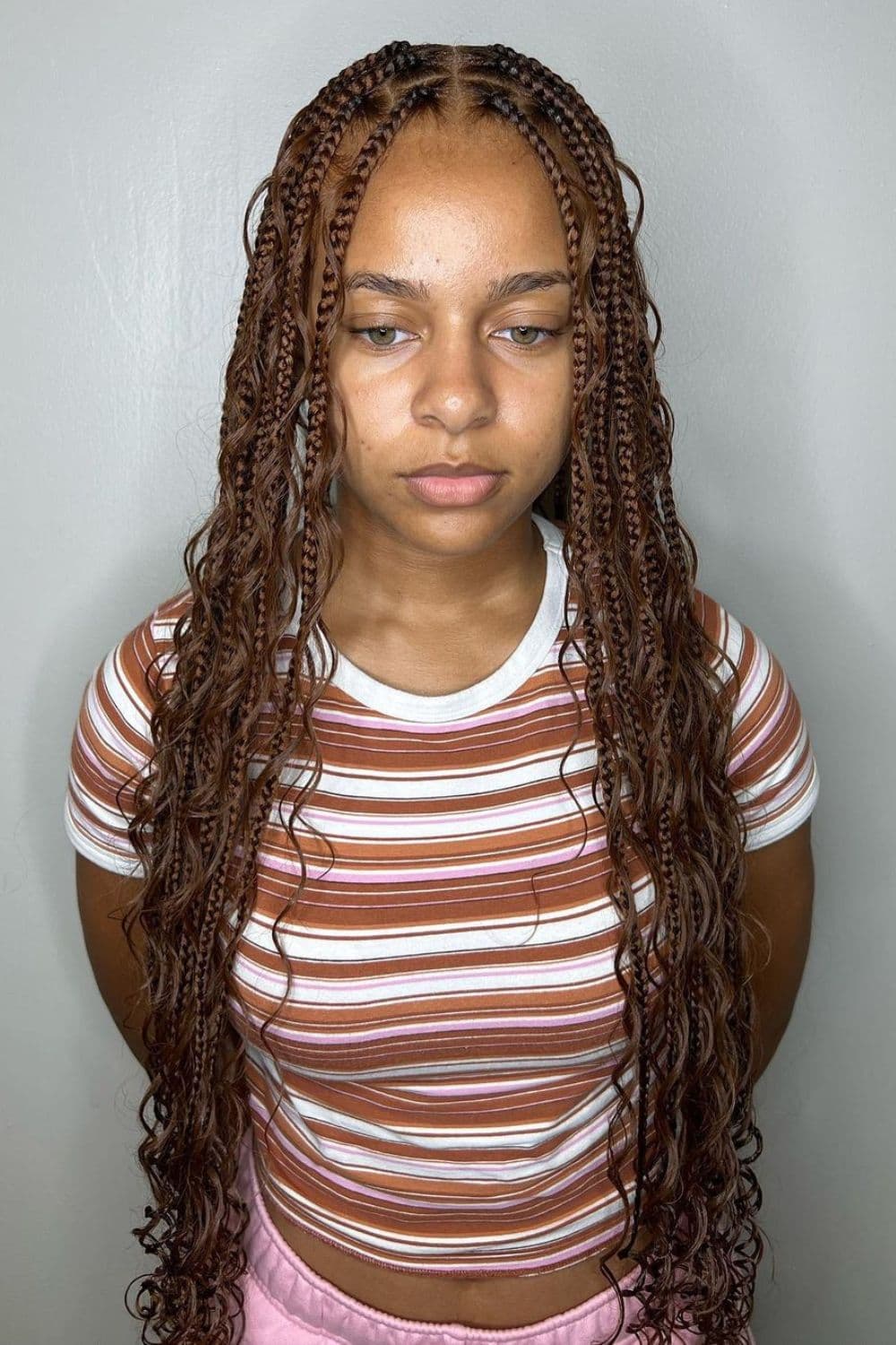 A woman in striped crop top with brown medium knotless braids.
