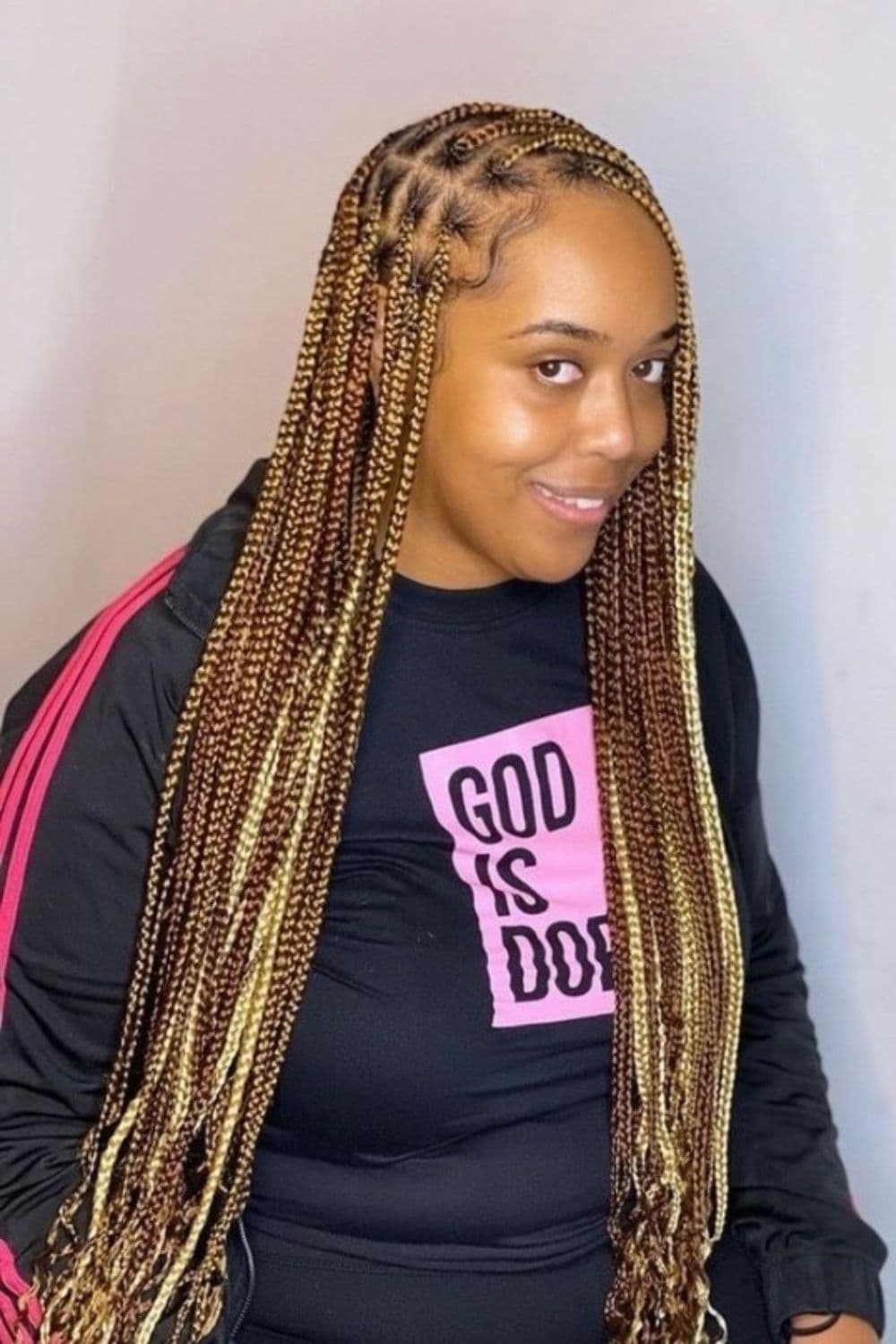 A woman wearing a black sweater with brown and blonde knotless braids.