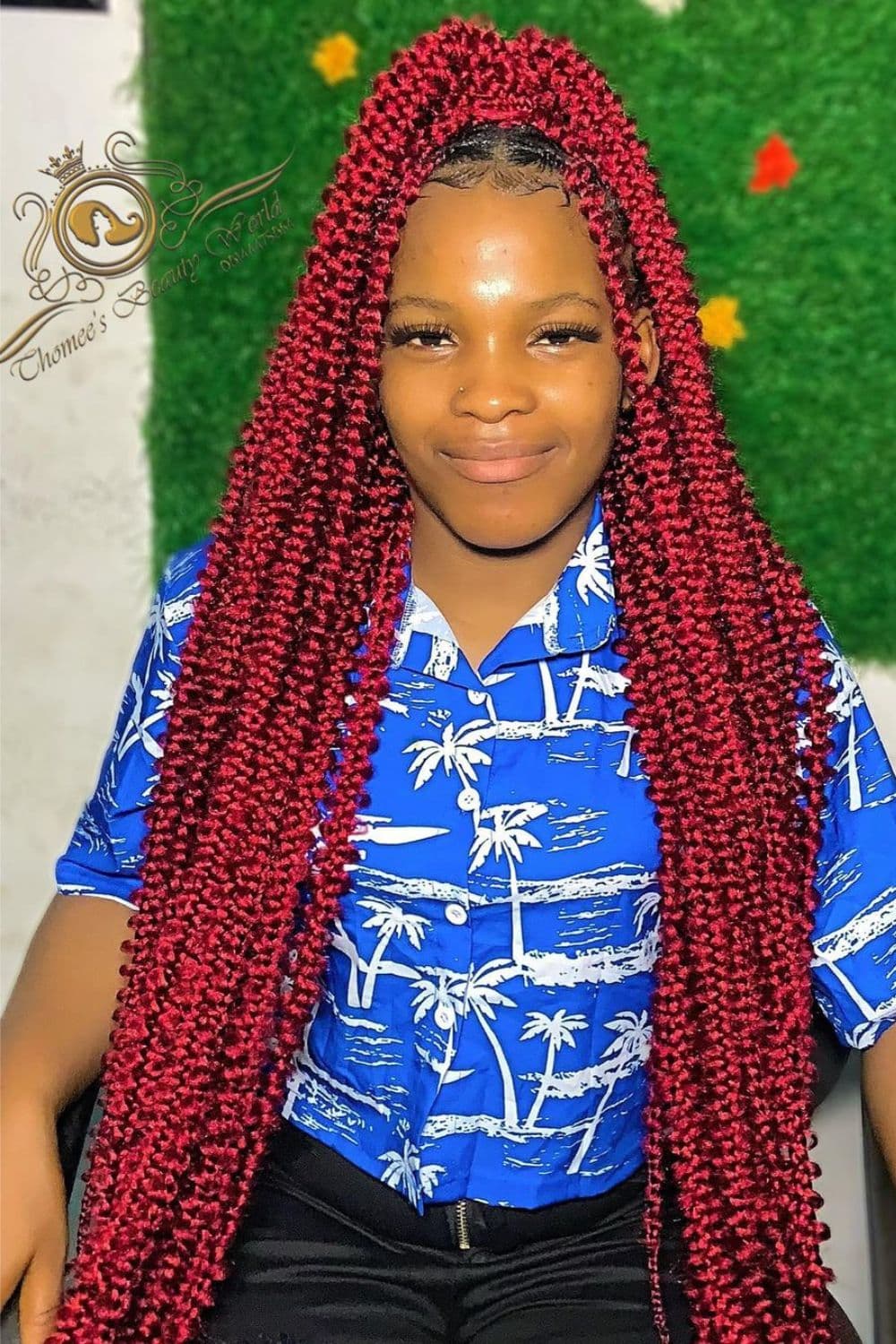 A woman wearing a blue palm tree printed blouse with a burgundy butterfly braid.