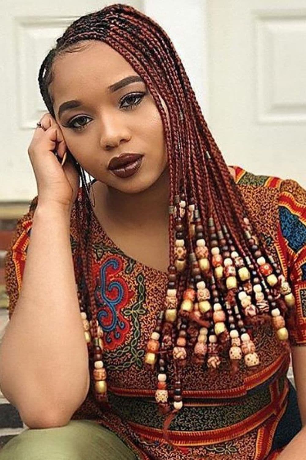 A woman with burgundy cornrows with beads.