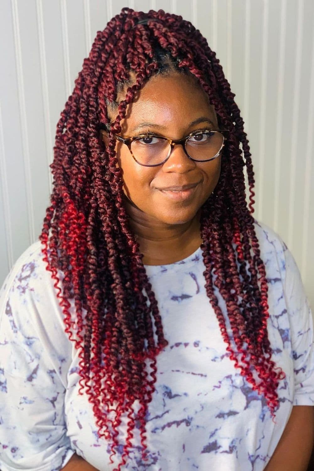 A woman wearing eyeglasses with burgundy passion twists.
