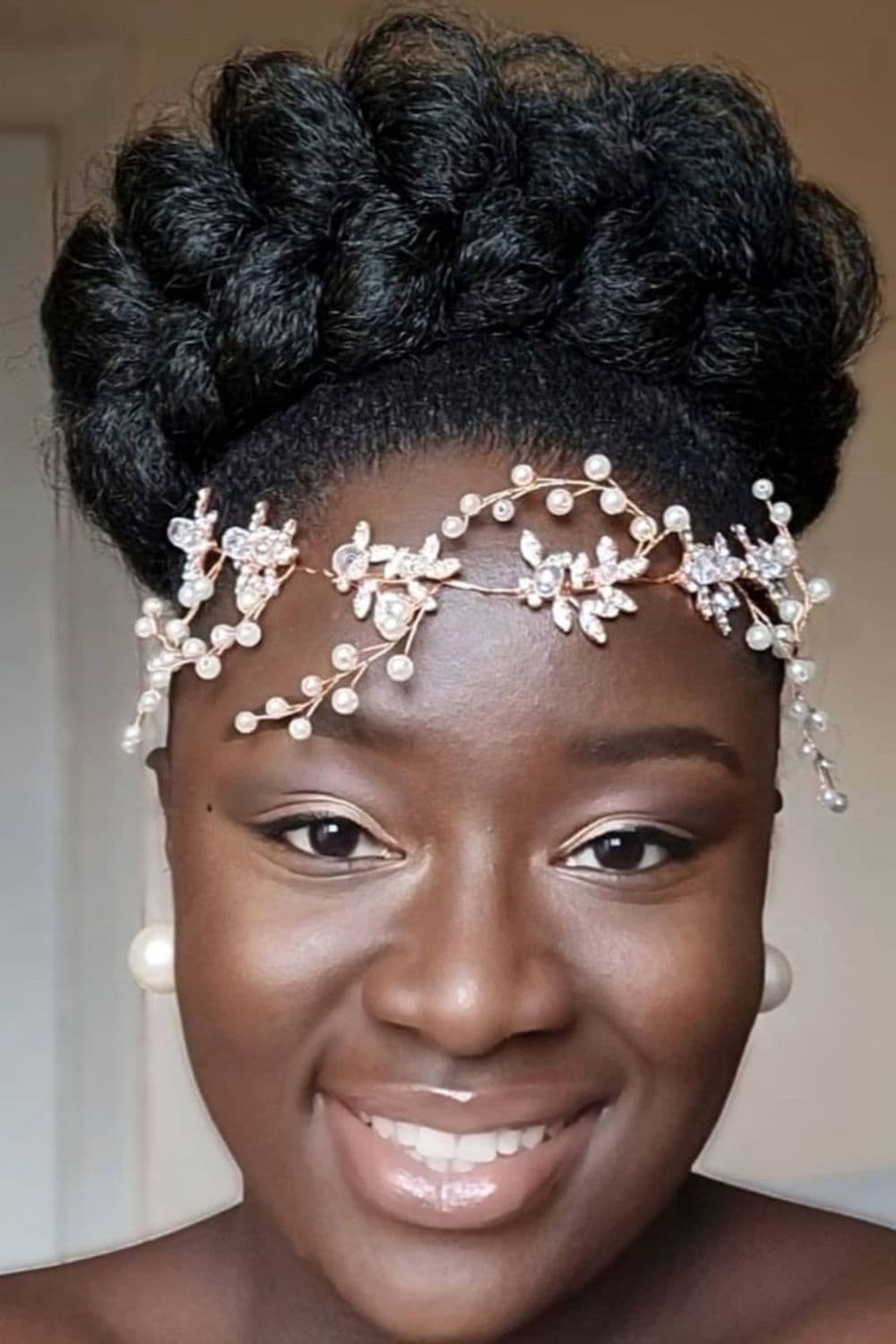 A woman with a black butterfly braid bun with an accessory on her forehead.