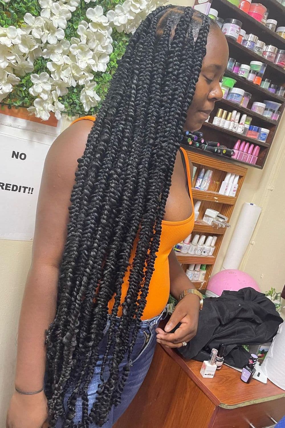 Side view of a woman standing with a black butterfly braid with curly ends.