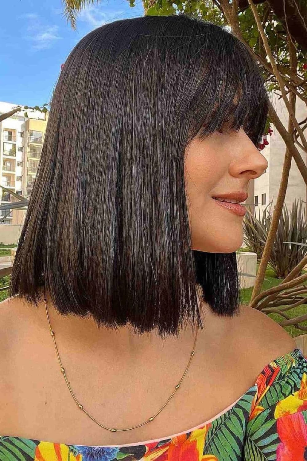 Side view of a woman with classic blunt weaves with bangs.