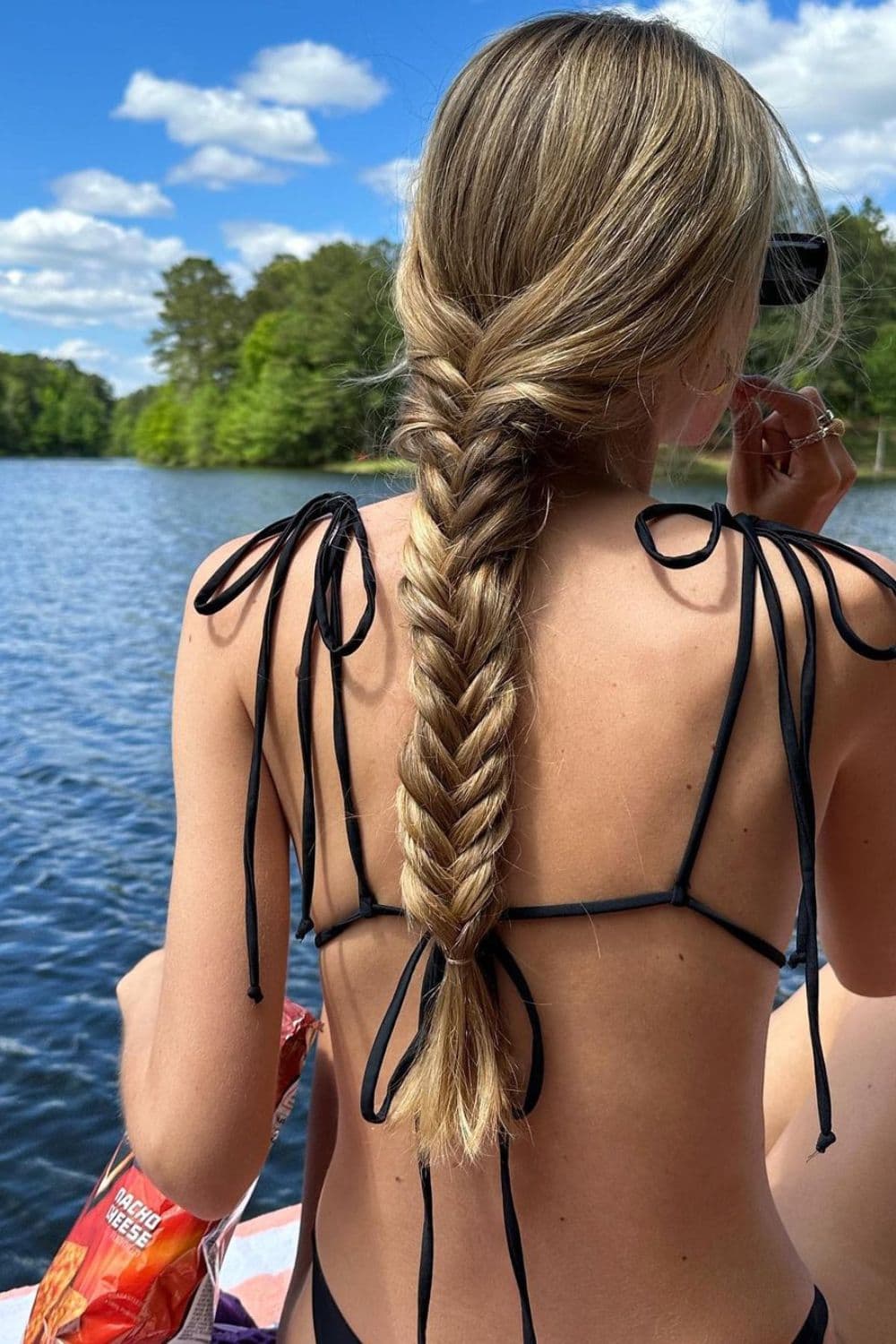 A woman in a black two-piece swimsuit with a blonde classic braided fishtail.