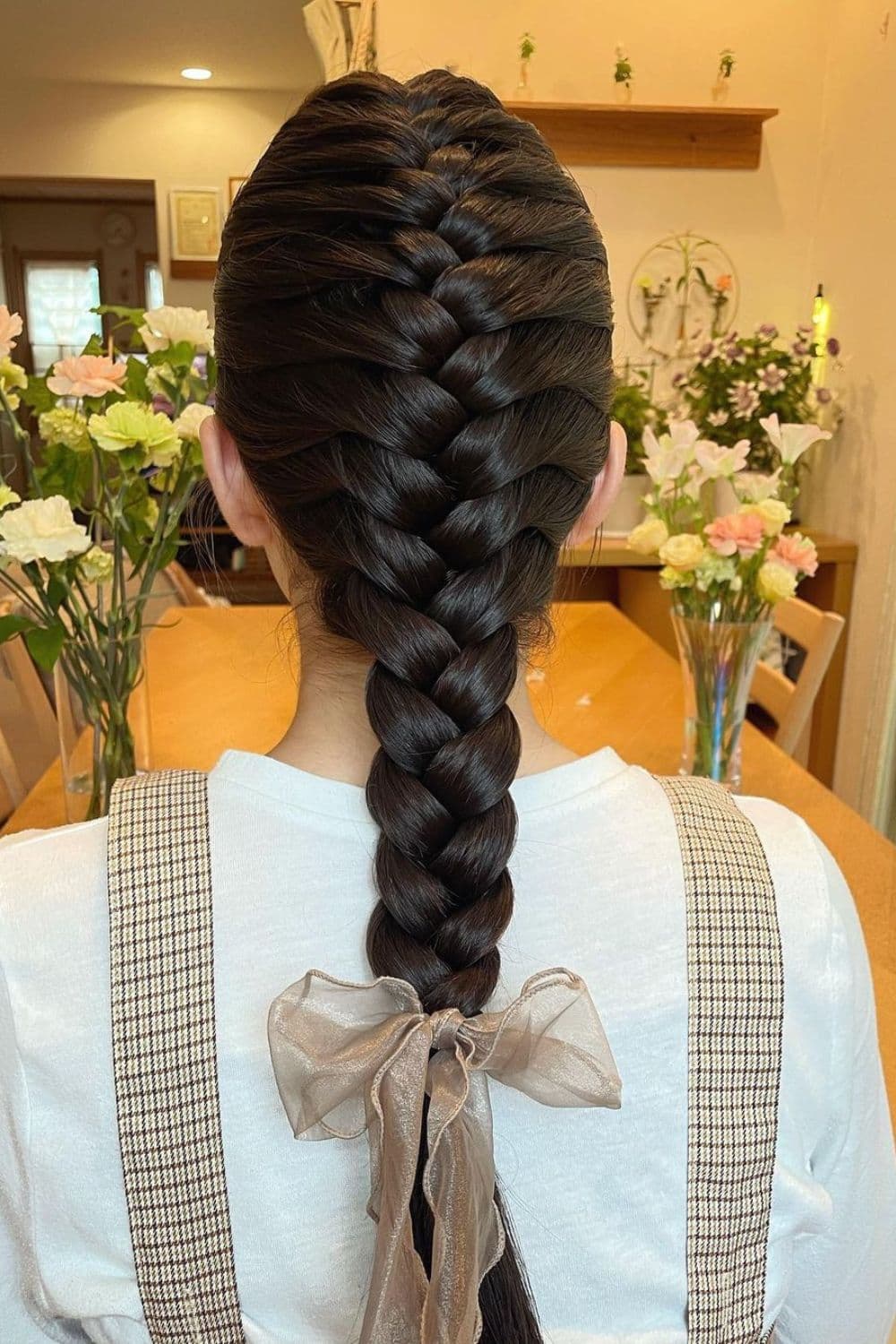 A woman with a classic French braid with ribbon at the end.