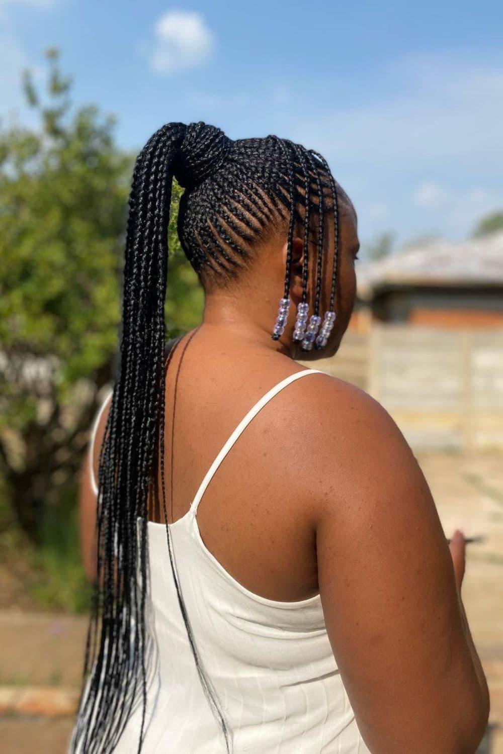 Side view of a woman with cornrows with beads ponytail.
