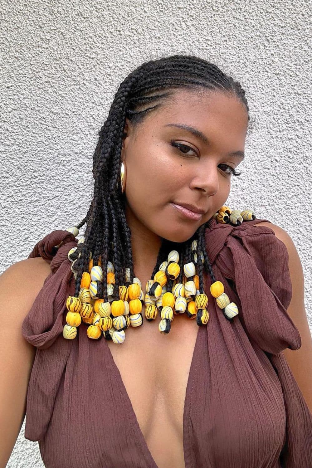 A woman with cornrows with wooden beads.