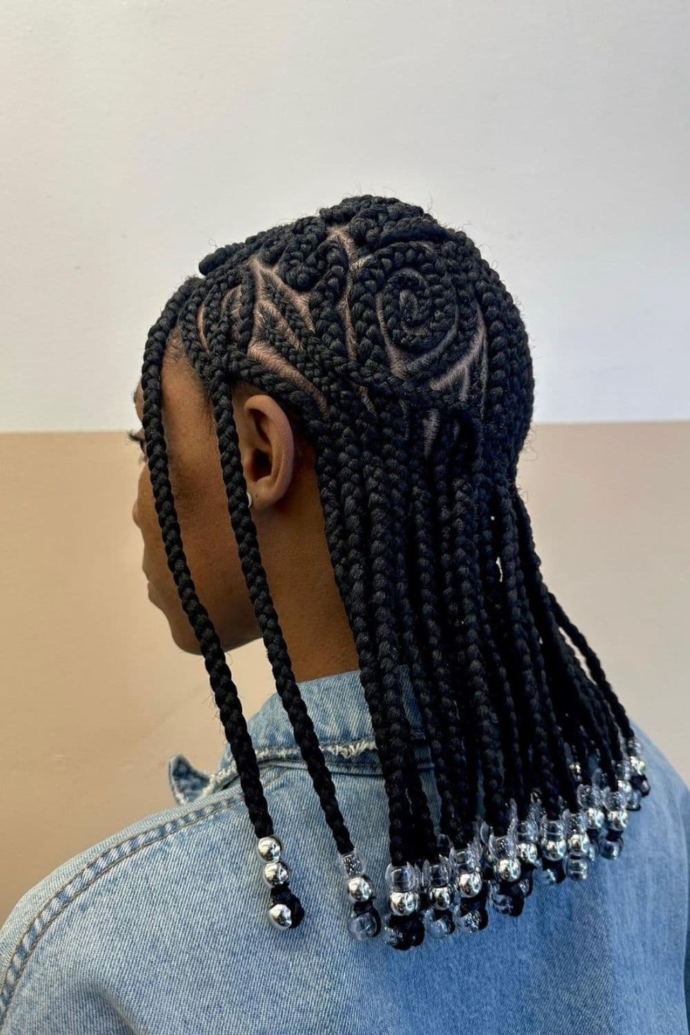 Side view of a woman wearing jacket jeans with creative box braids with silver and clear beads.