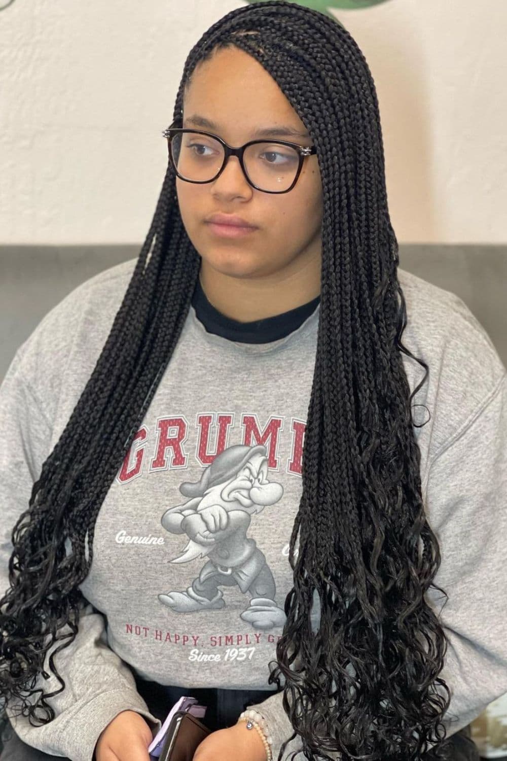 A woman wearing a gray sweater with black crochet box braids with curly ends.