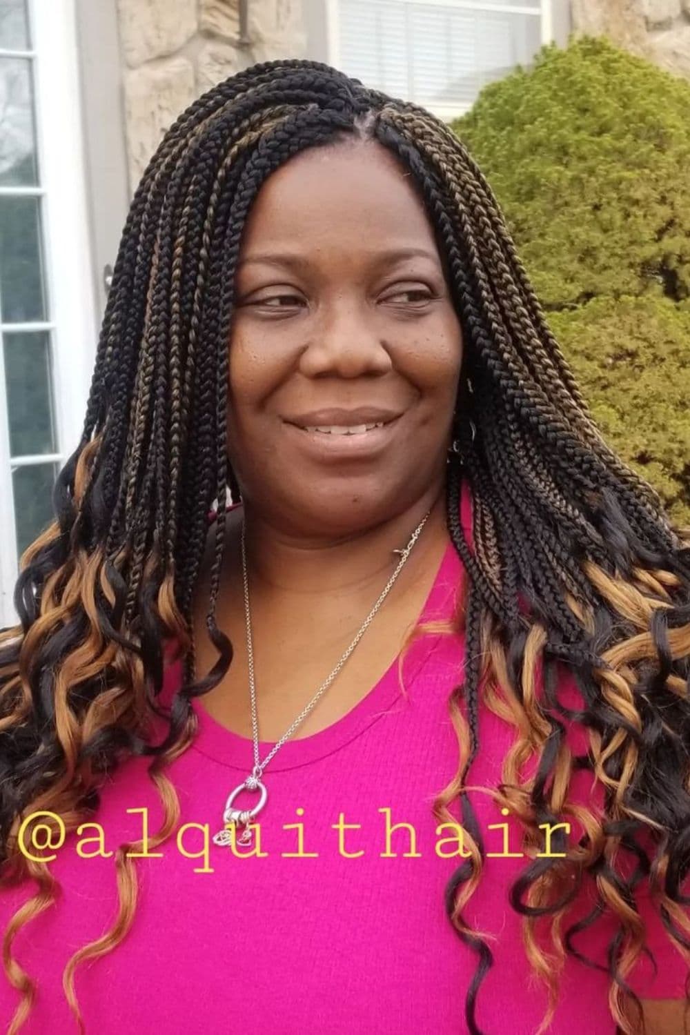 A woman with brown and black crochet braids with curly ends.