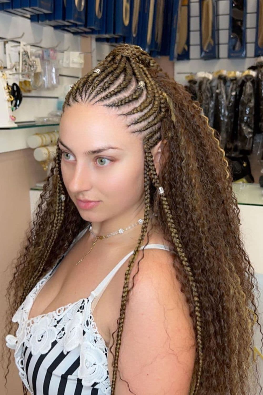 A woman with brown crochet and cornrows with silver hair cuffs.