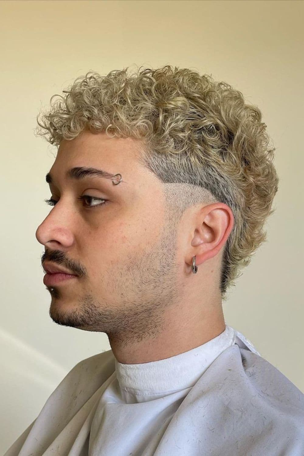 Side view of a man with short curly blonde mullet.