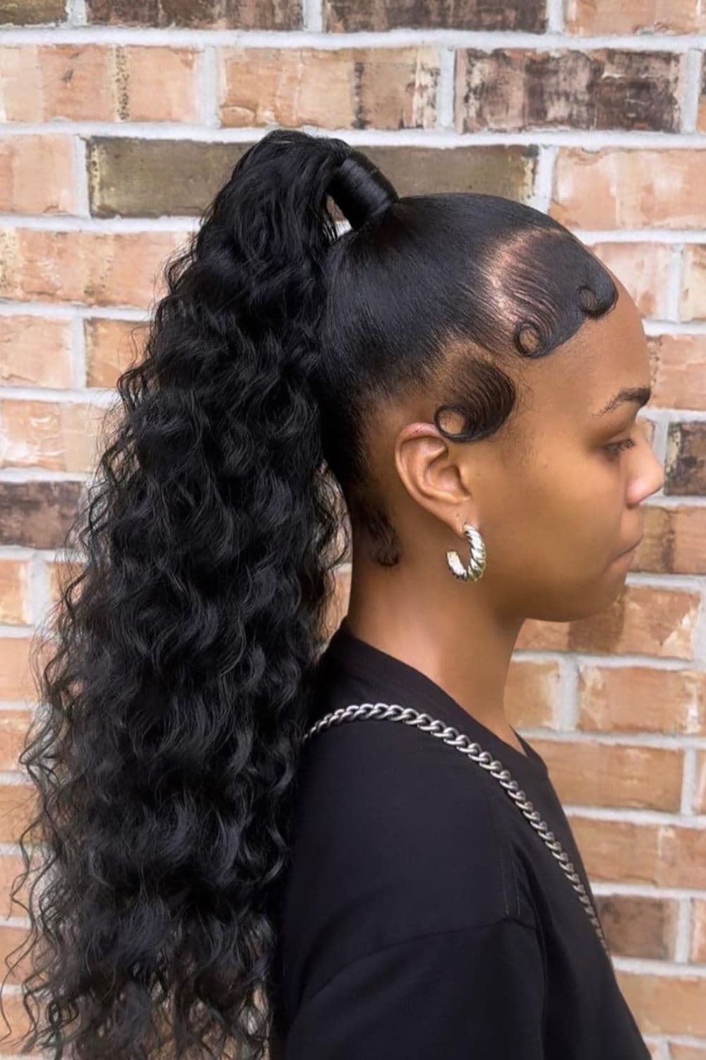 Side view of a woman with a black curly high ponytail.