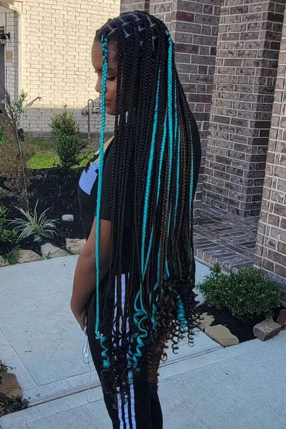 Side view of a woman with black and light blue medium knotless braids.