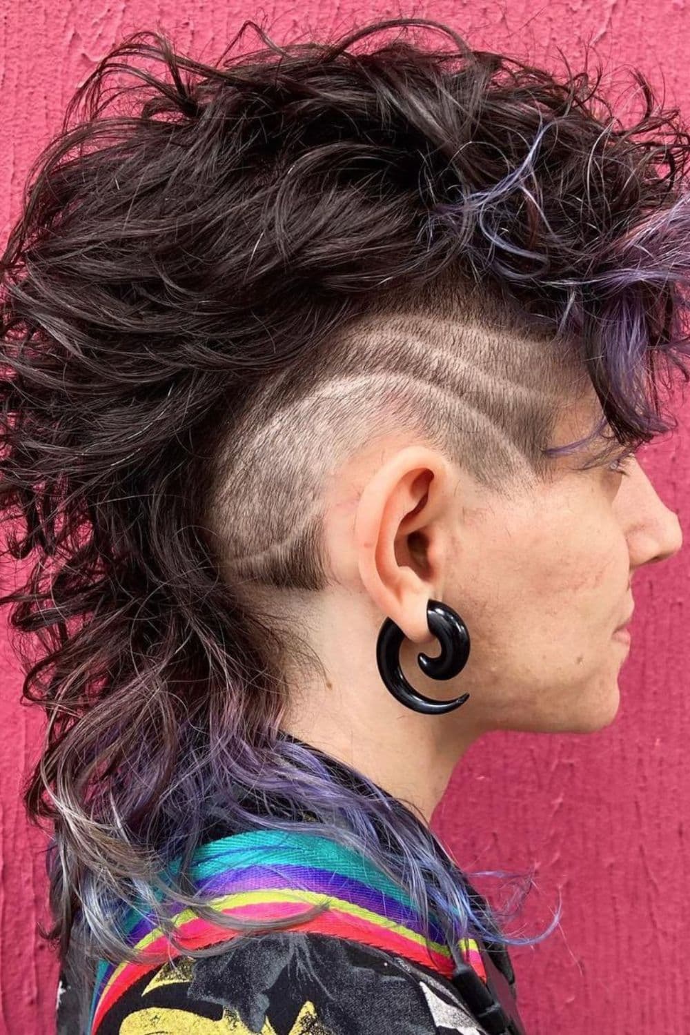 Side view of a man with curly mullet with hair tattoo.