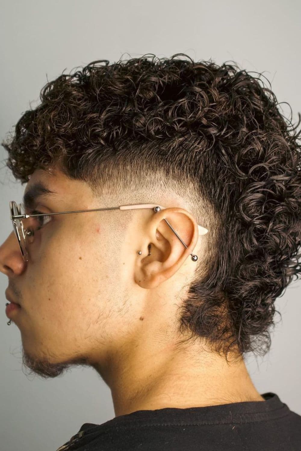 Side view of a man with curly mullet with low fade.
