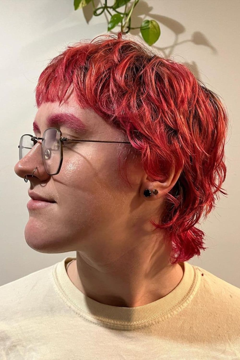 Side view of a man wearing eyeglasses with curly pink mullet.