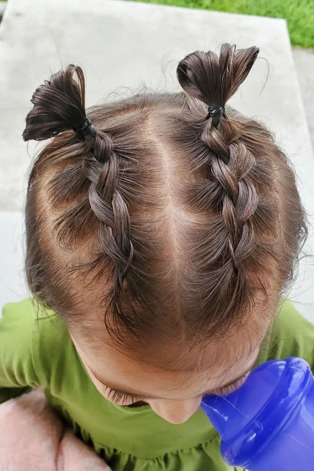 A little girl with double Dutch braids into high buns.
